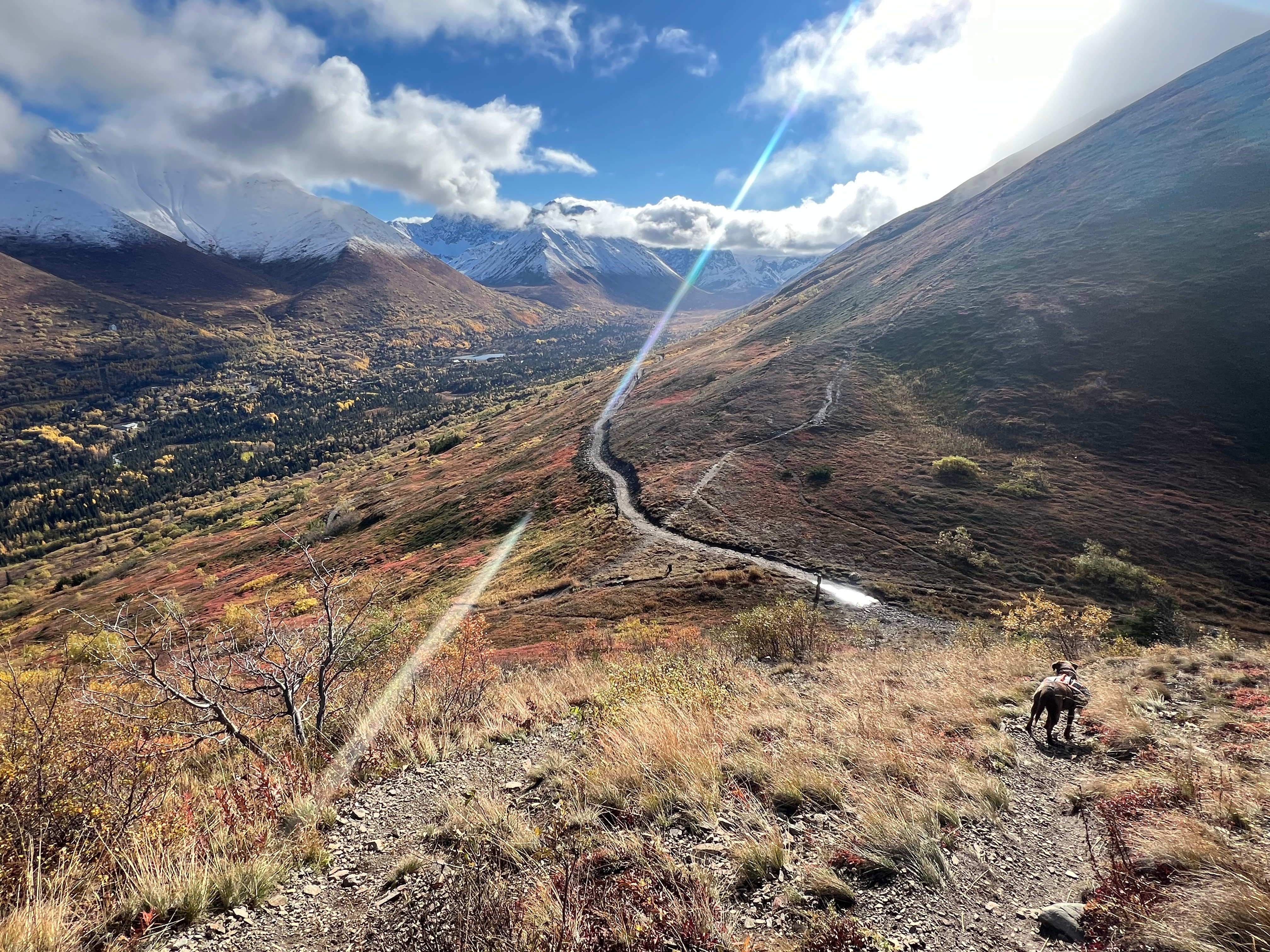 A trail intersection is below with a long valley in the distance.