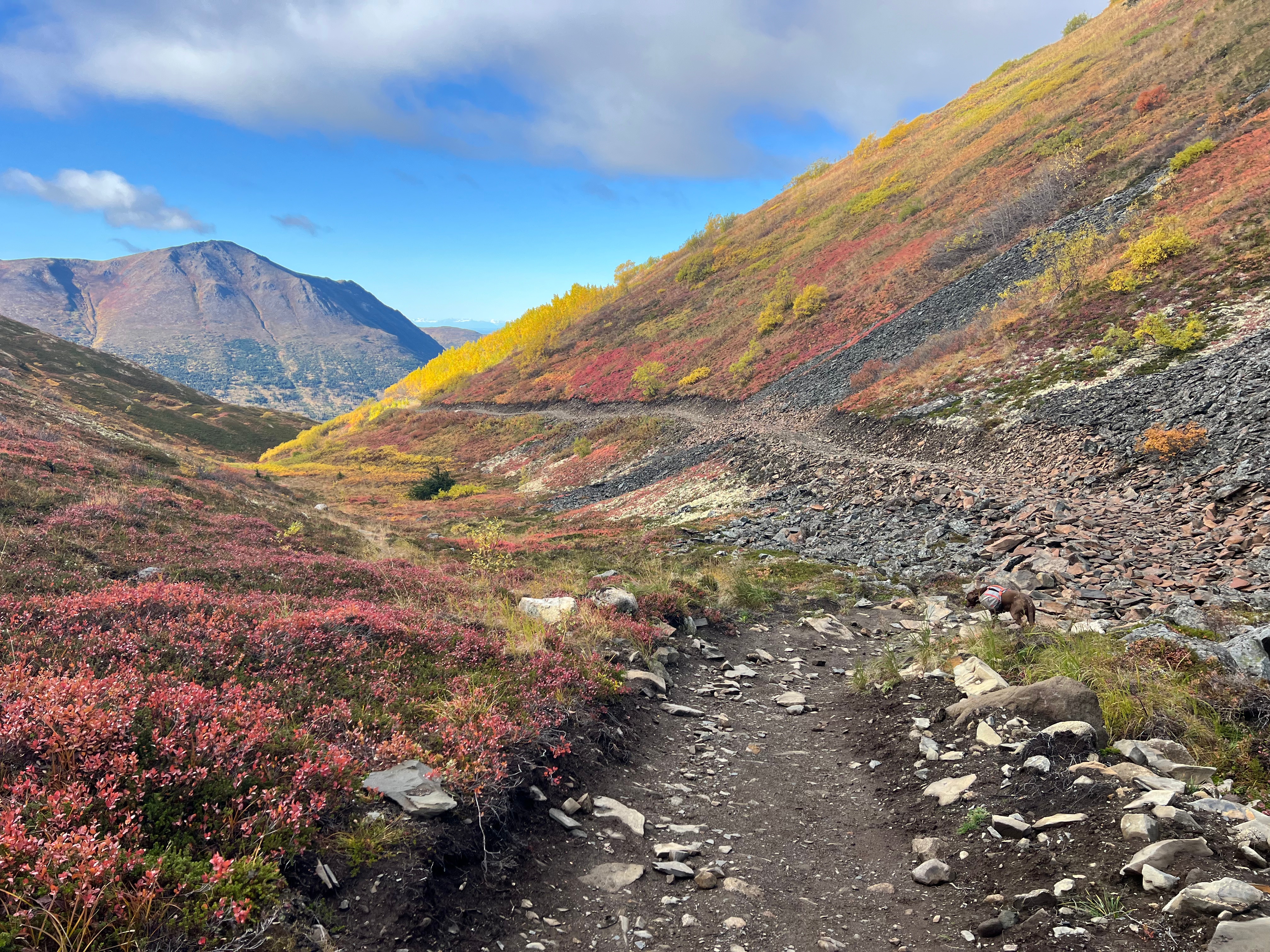 Brightly colored fall vegetation on slopes. A rocky trail winds between the two slopes