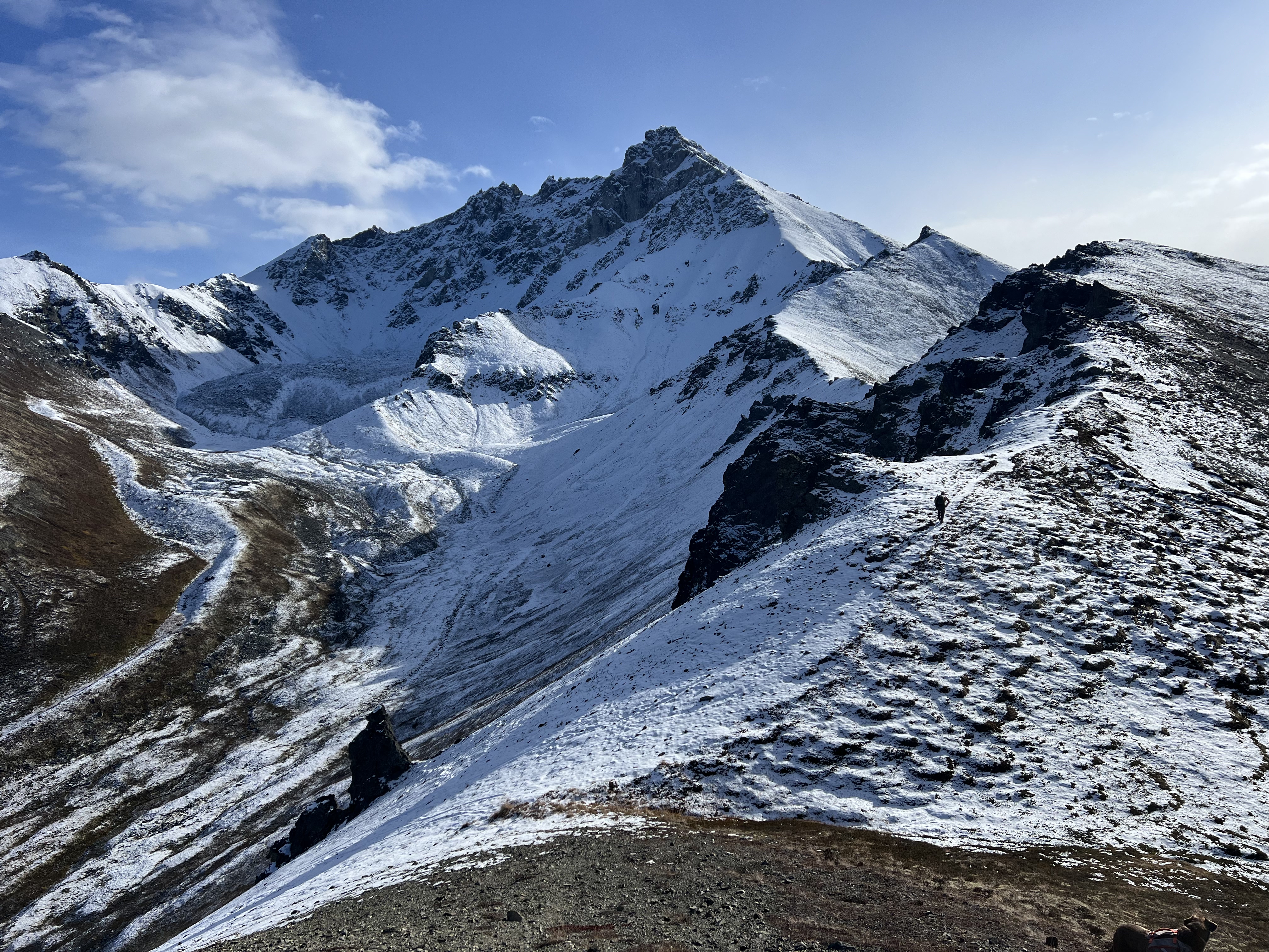 Person walking up the ridgeline with giant snowcapped mountain beyond