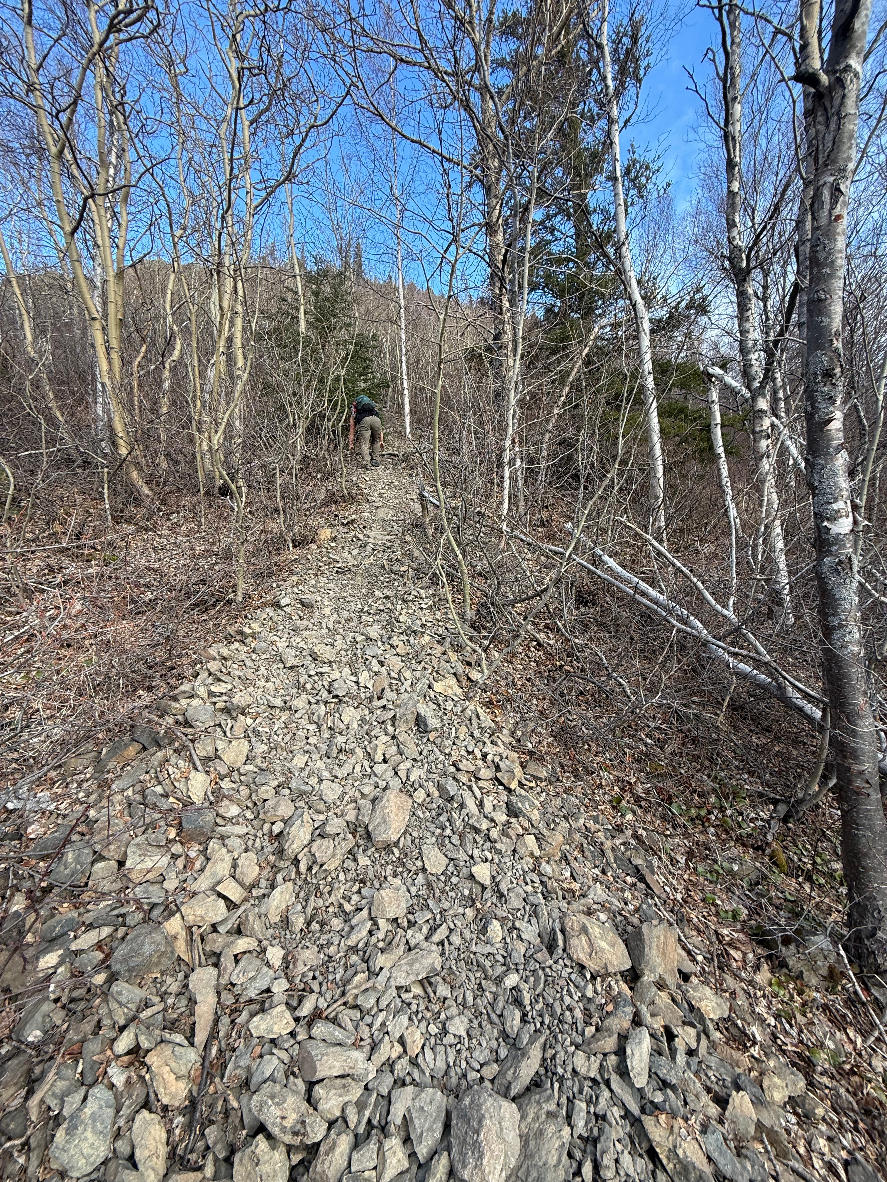 A hiker climbs up a steep, narrow and rocky path