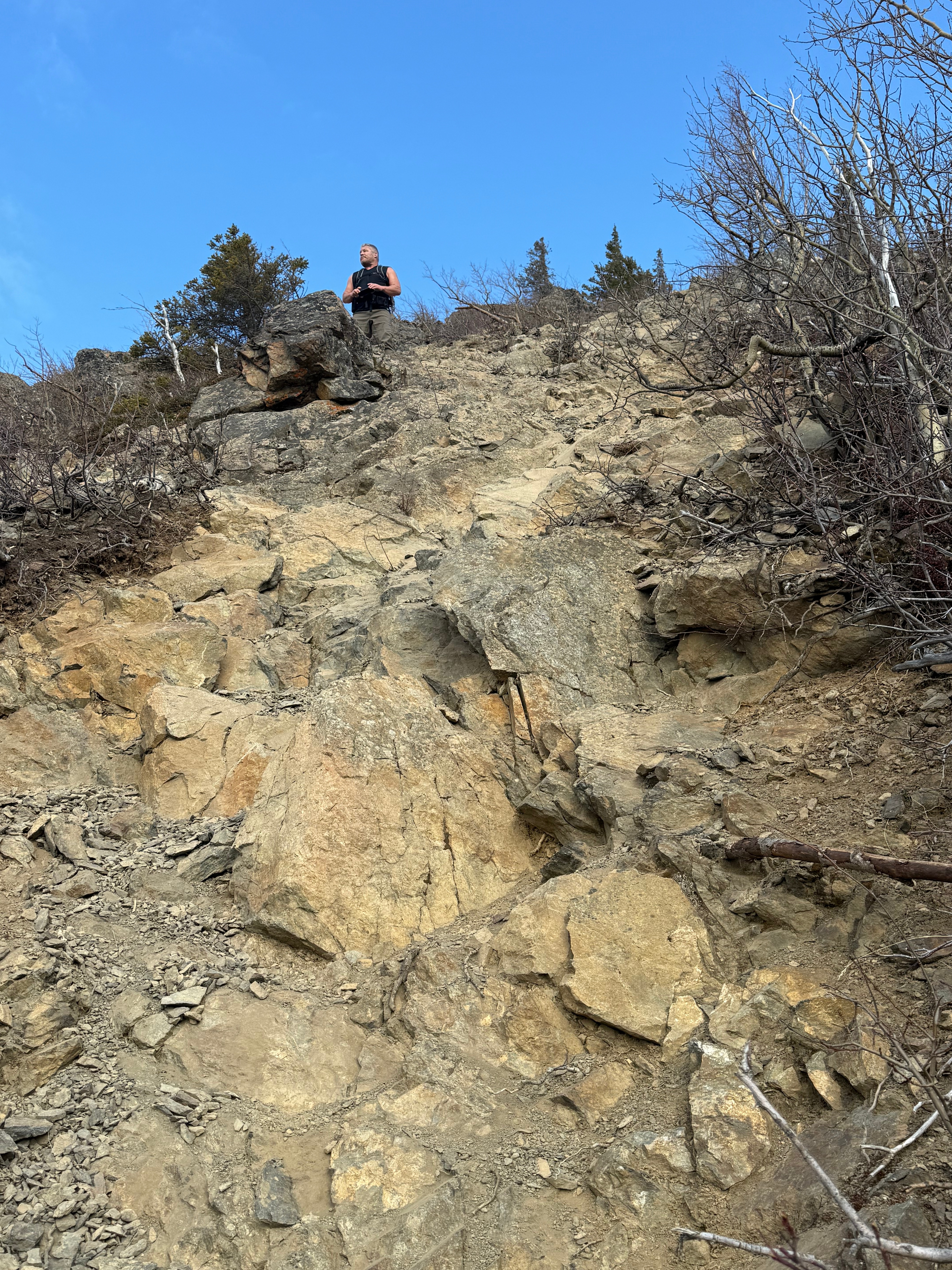 A hiker stands atop a steep, rocky section of trail