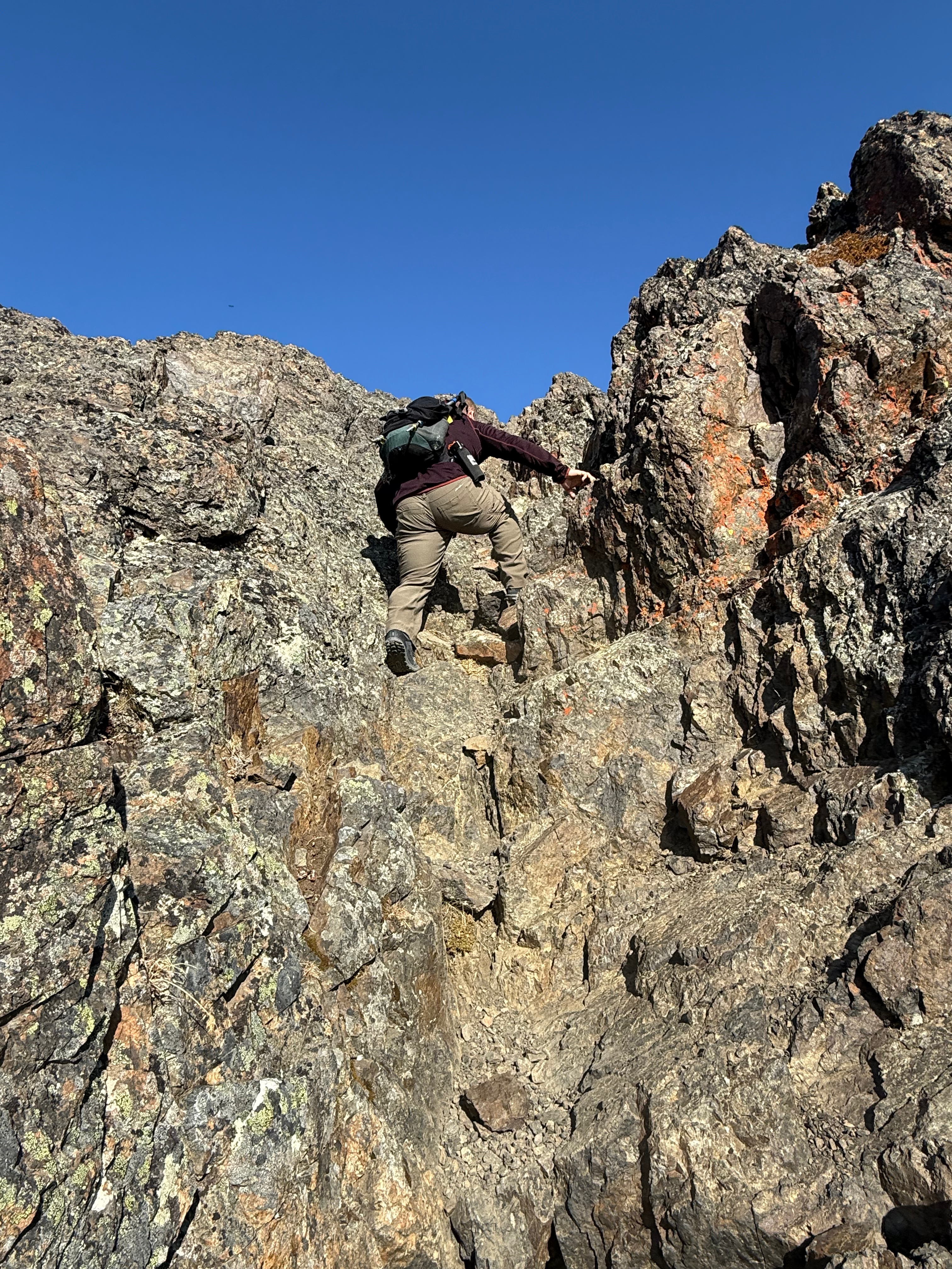 A hiker climbs up a vertical rock face.