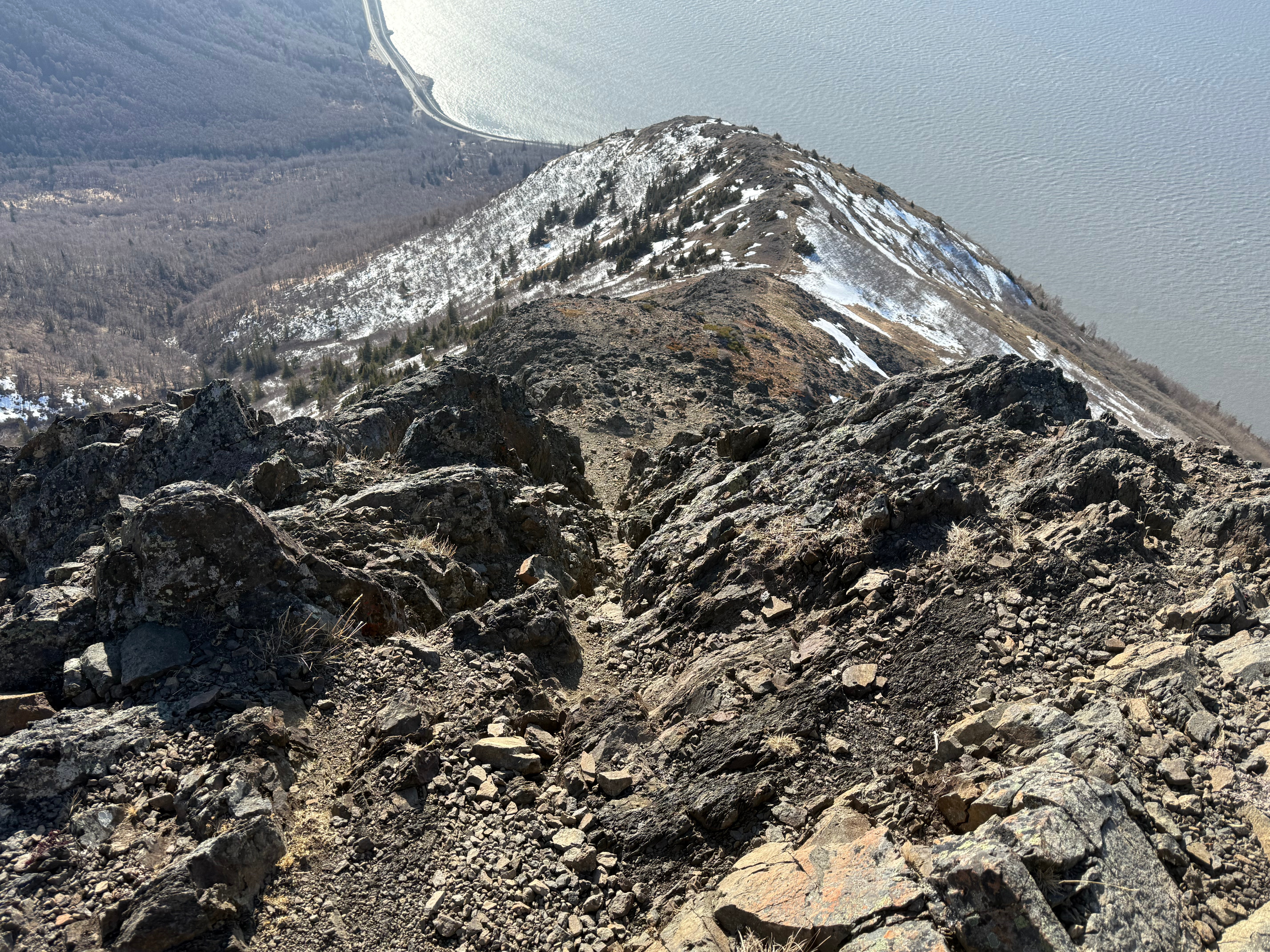 Facing down toward the ocean and the lower plateau of the trail, a steep, rocky chimney shaped trail drops off steeply