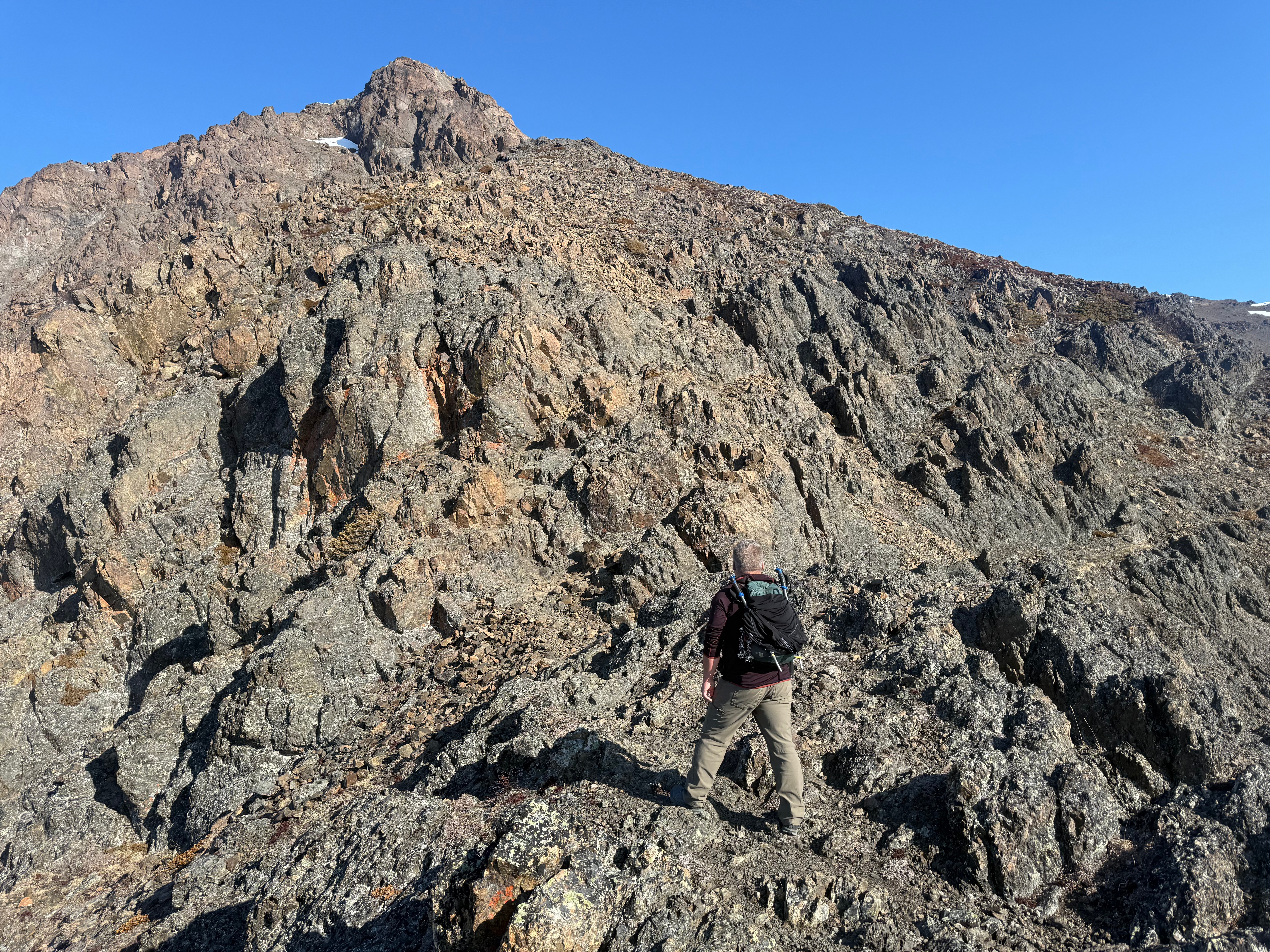 A hiker stands below the summit section of the mountain.