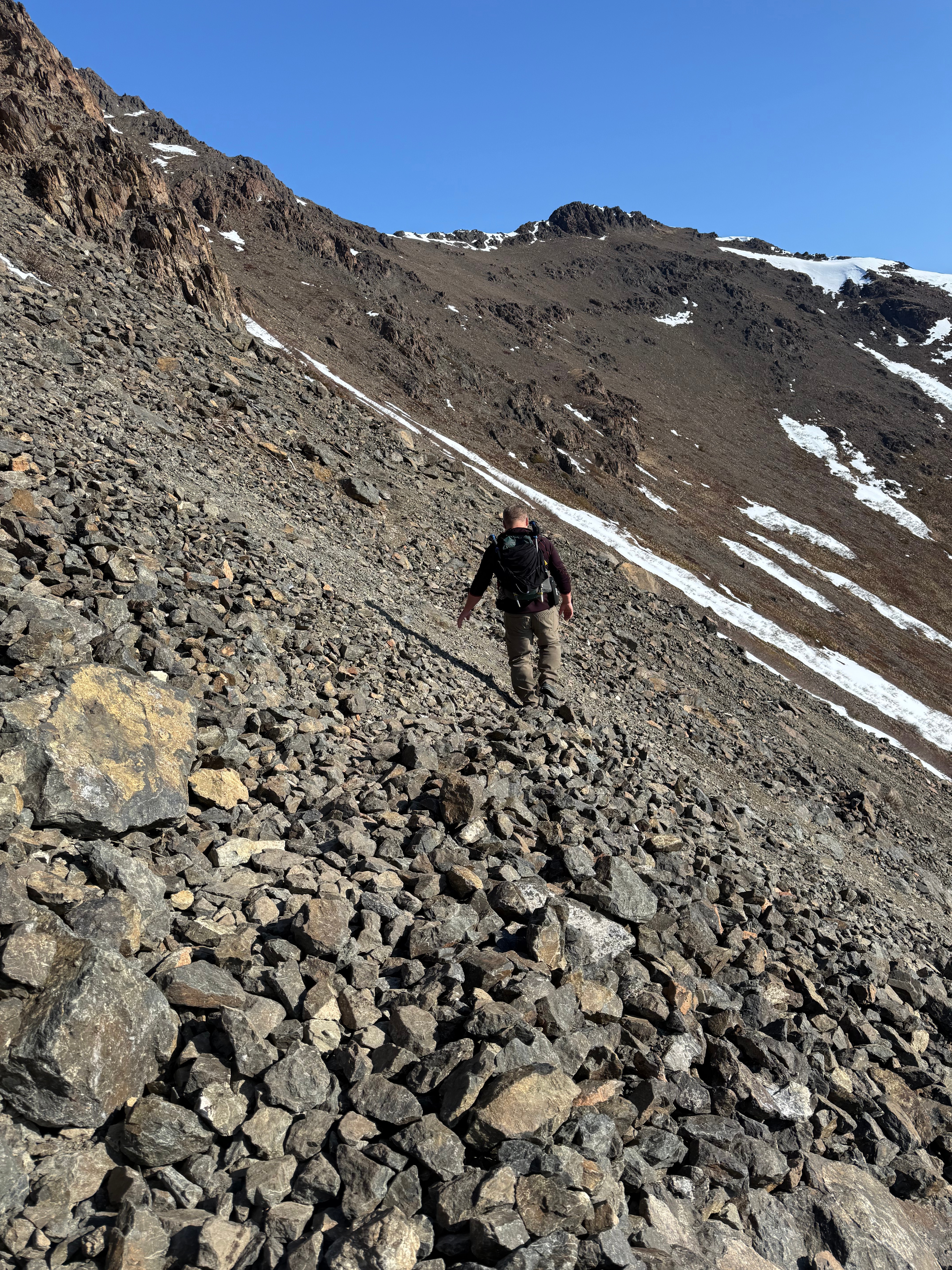 A hiker traverses a rocky section of the steep slope.