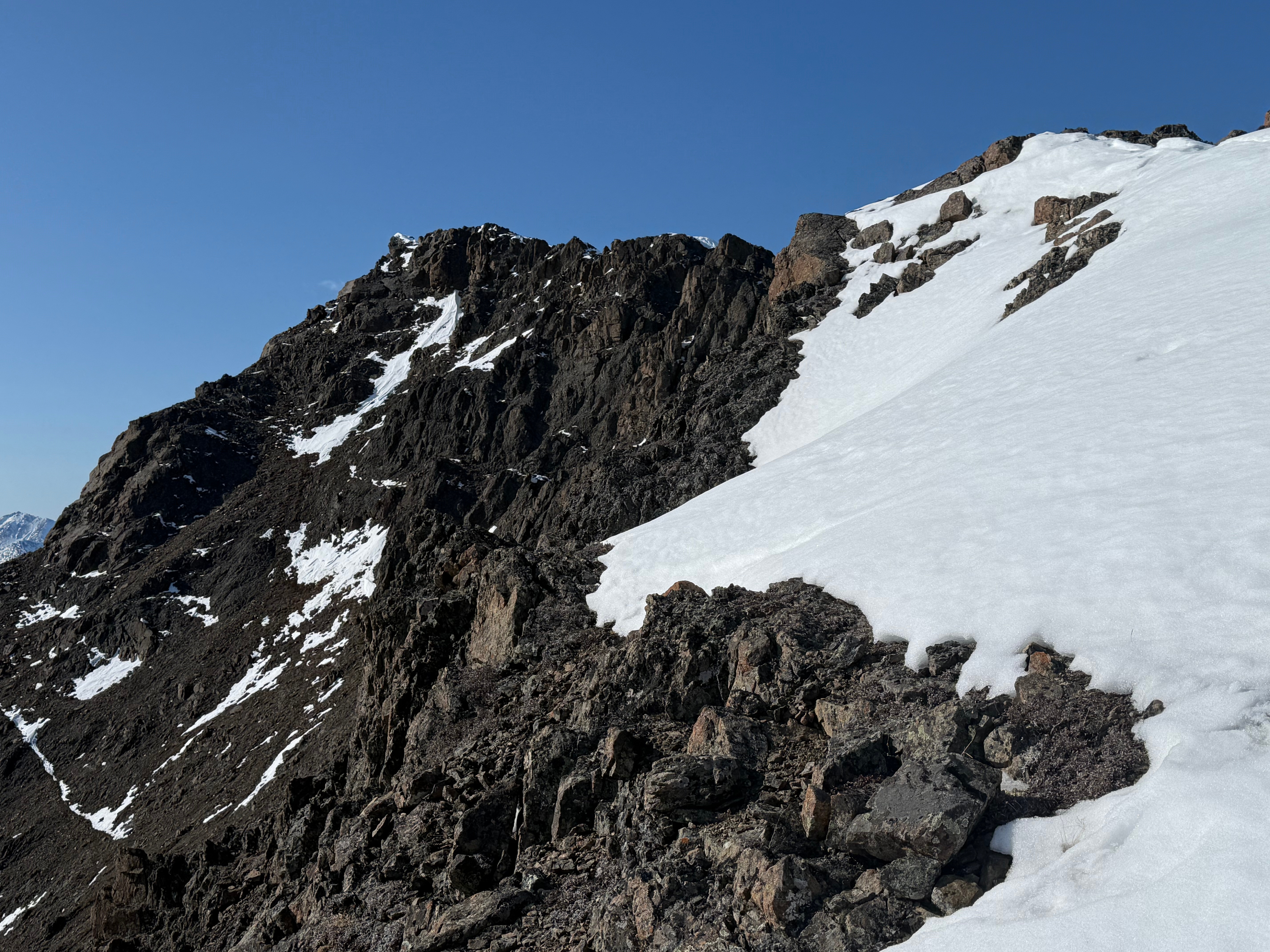 The summit rises up beyond a small snowfield and a short summit ridge.