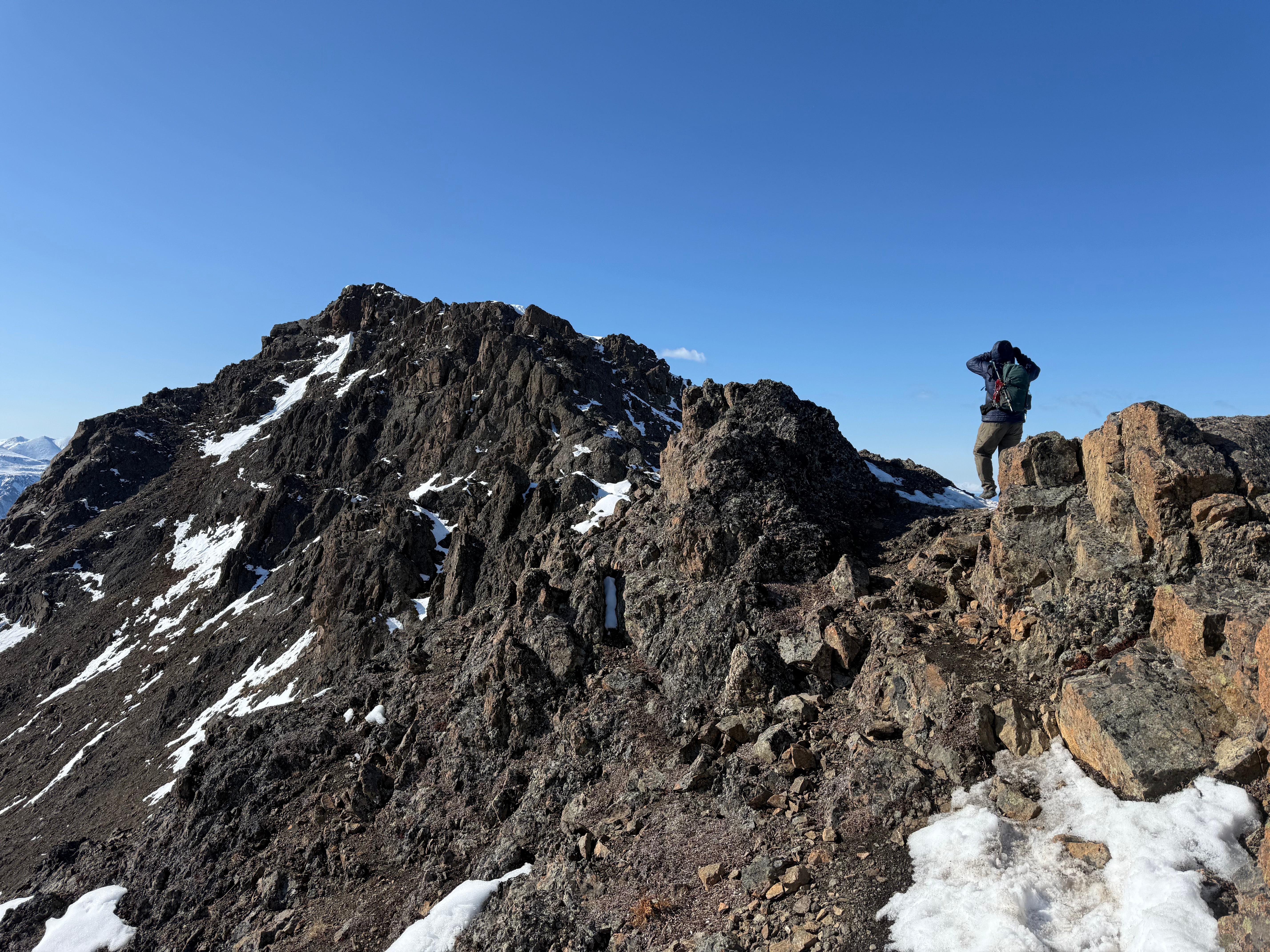 A hiker walks next to rocky outcroppings on the summit ridge.