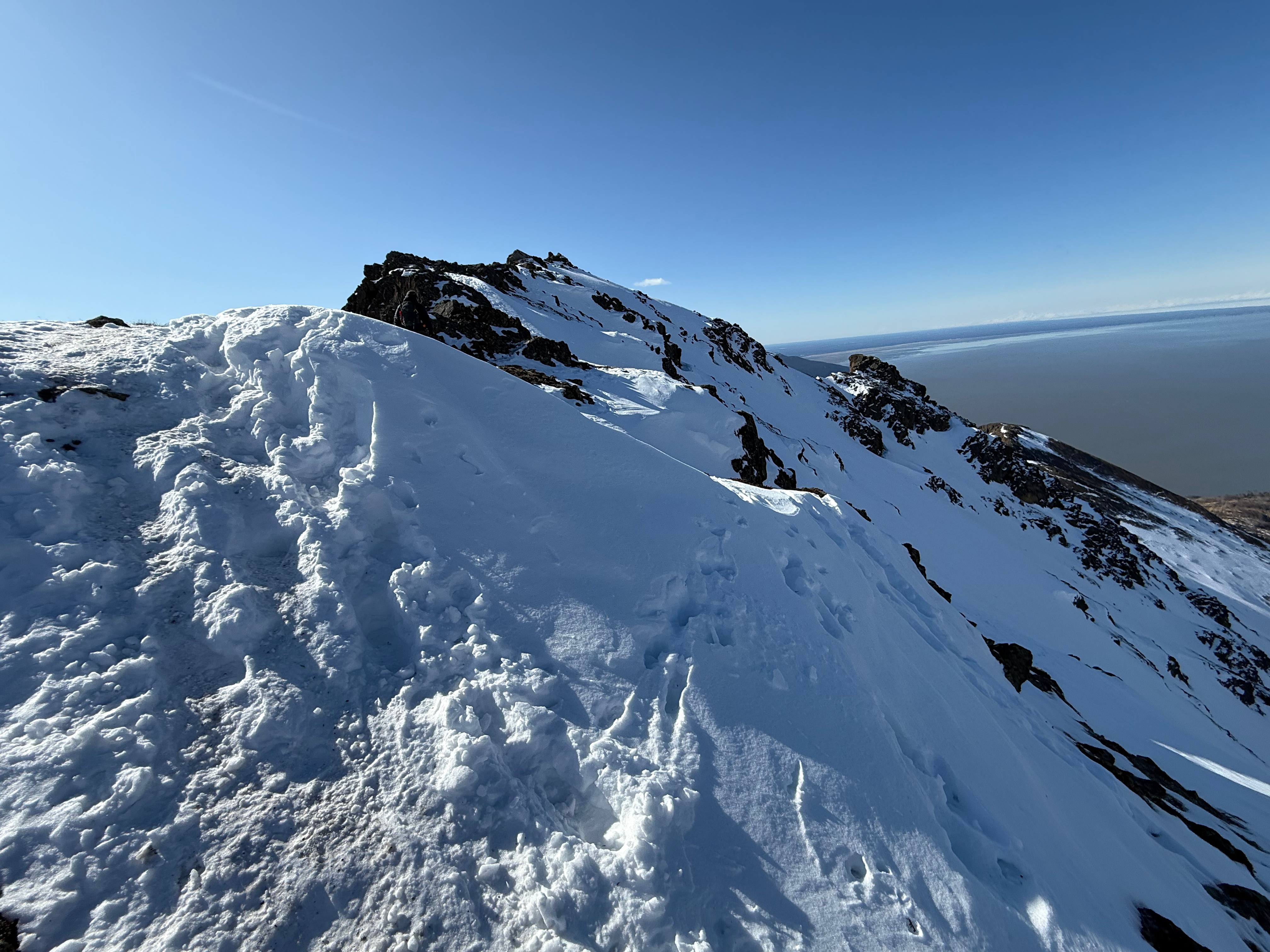 A steep, snow covered slope rises to the summit of Rainbow Peak.