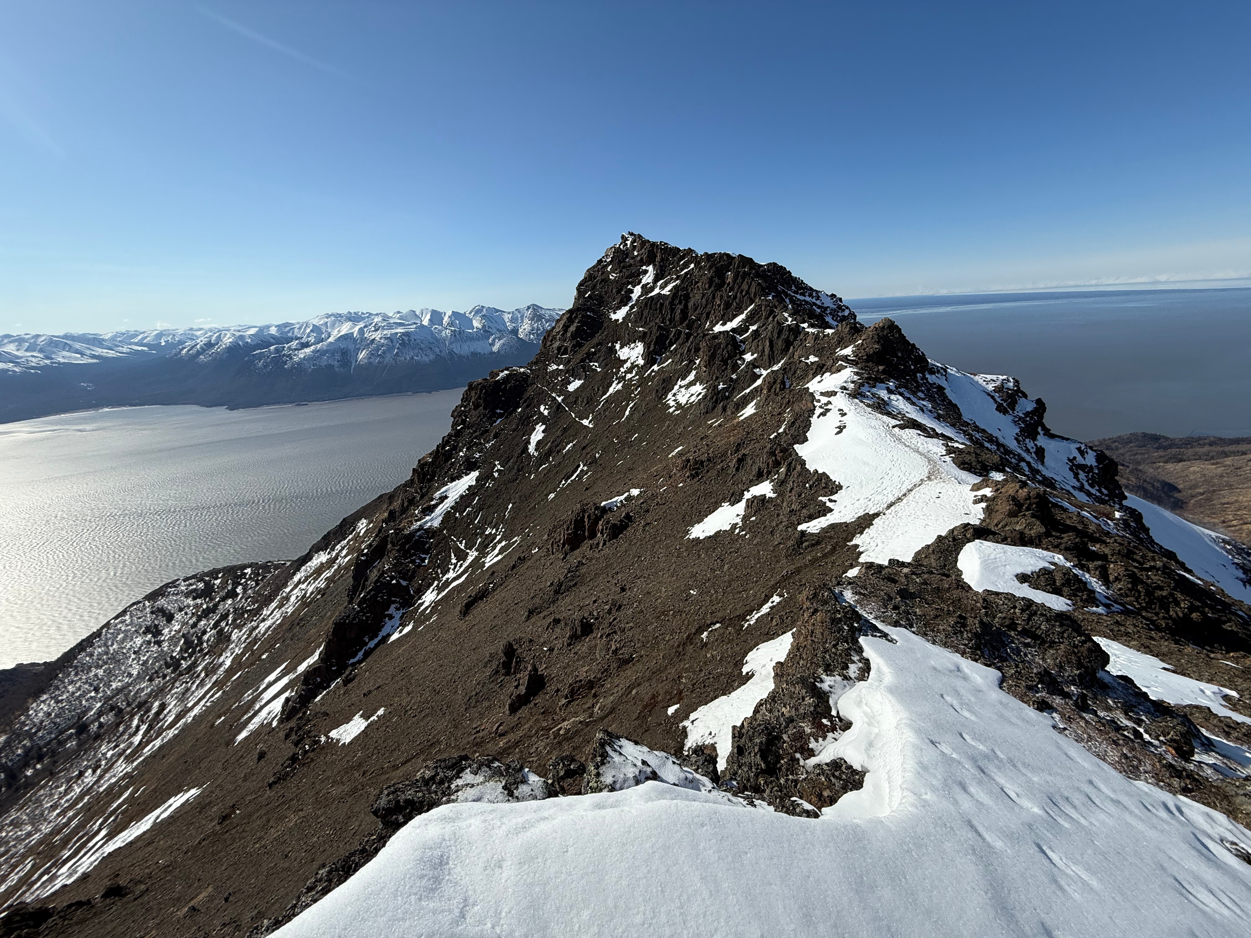 Facing back towards Rainbow summit. A faint path through the snow drops down onto the scree slope below.