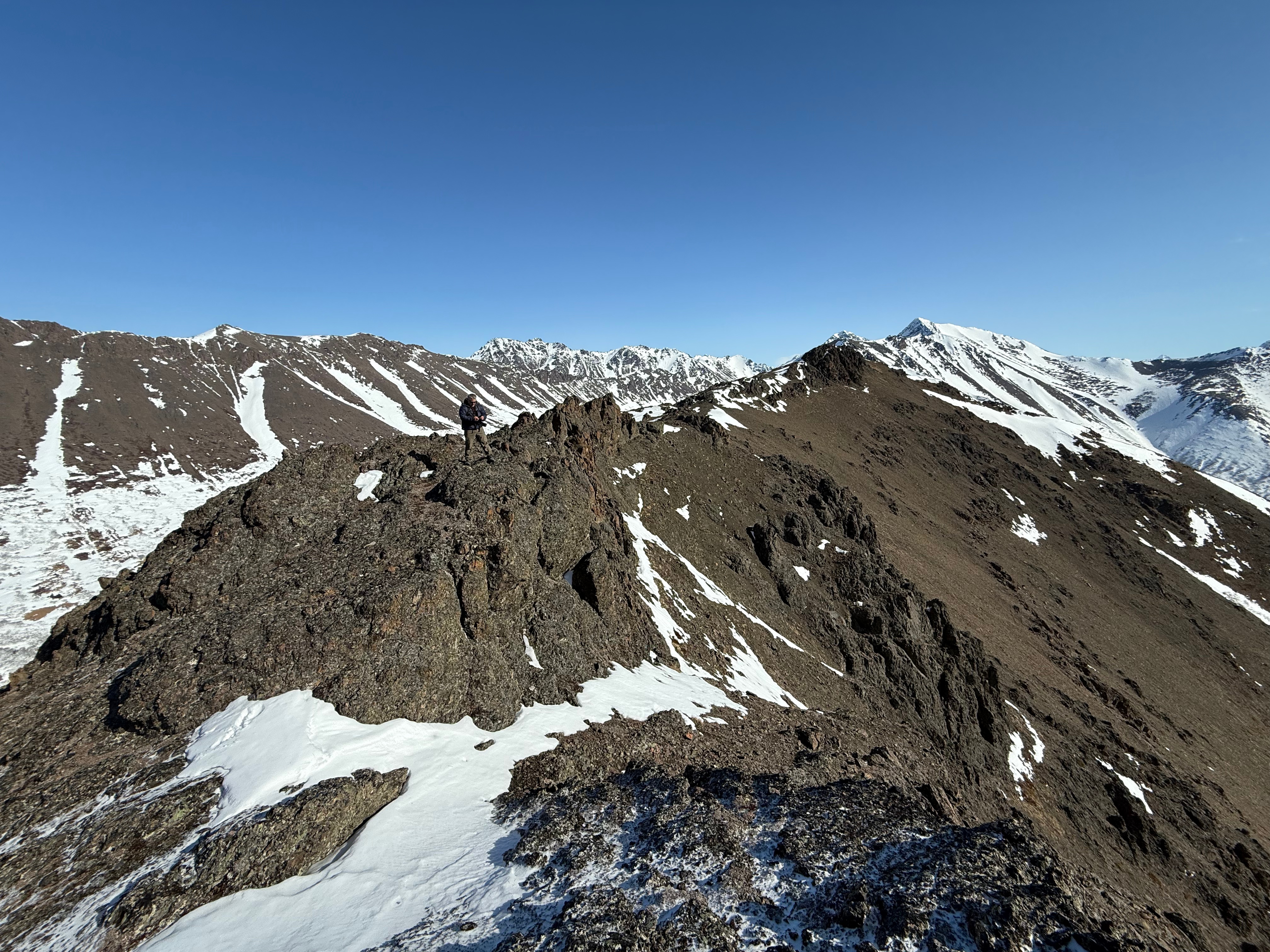 A hiker stands on rocks piled up on the summit ridge.
