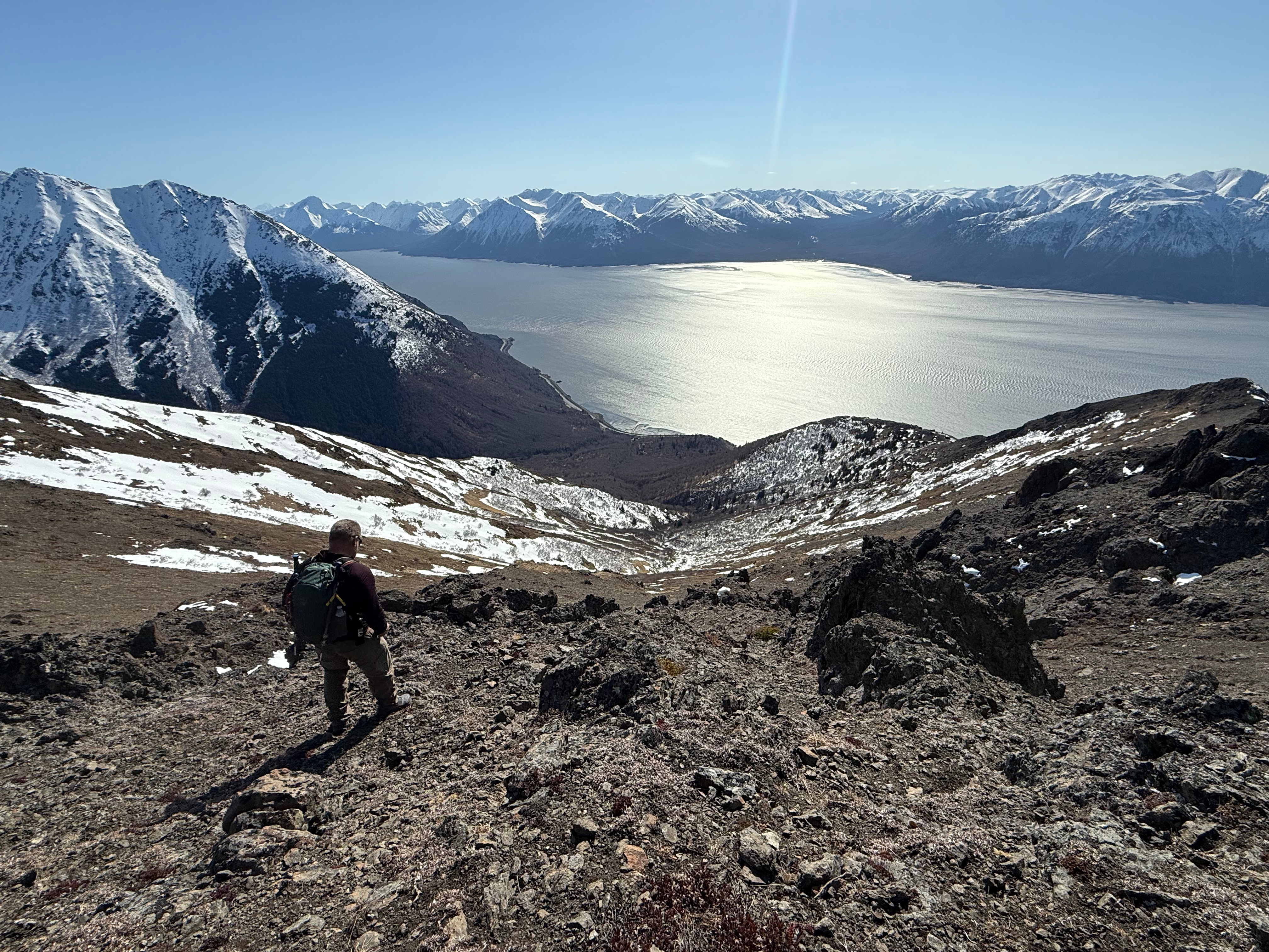 A hiker stands overlooking the lower steps of the Rainbow Peak Trail. The ocean and highway are far below.