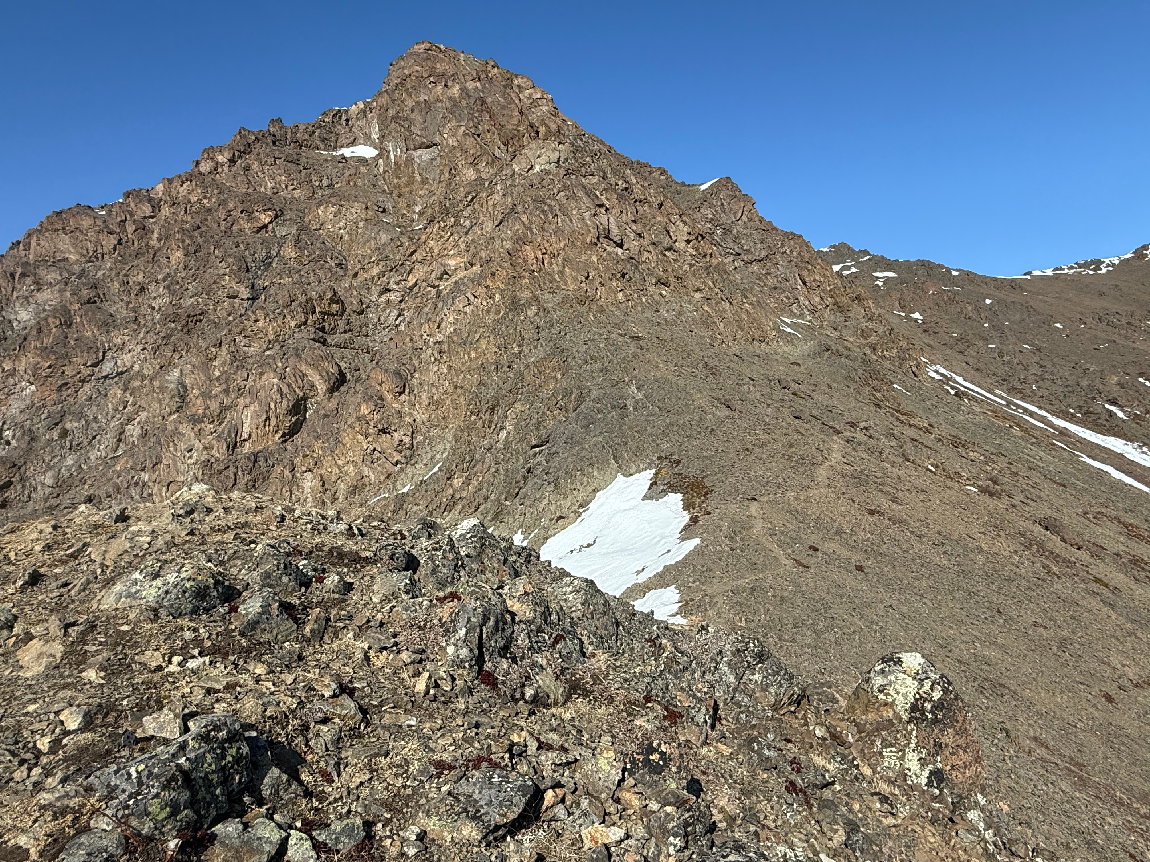 A gray bootpath is visible across the first part of the scree slope below the summit