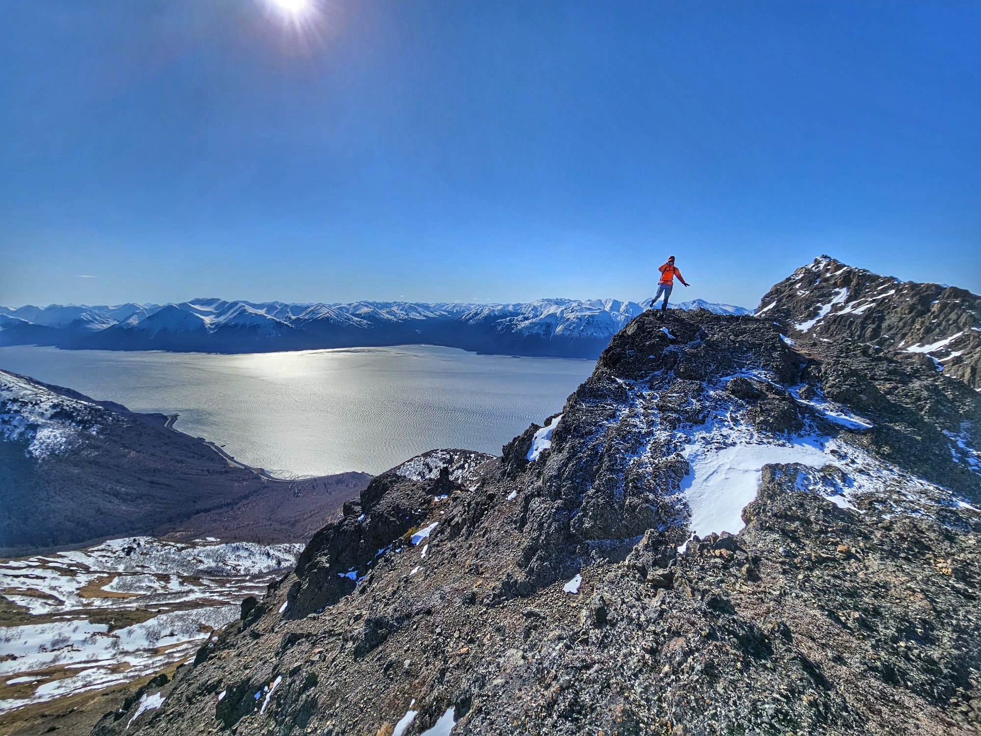The author is standing on one foot and touching her nose. She is high up next to a steep dropoff, the ocean is below