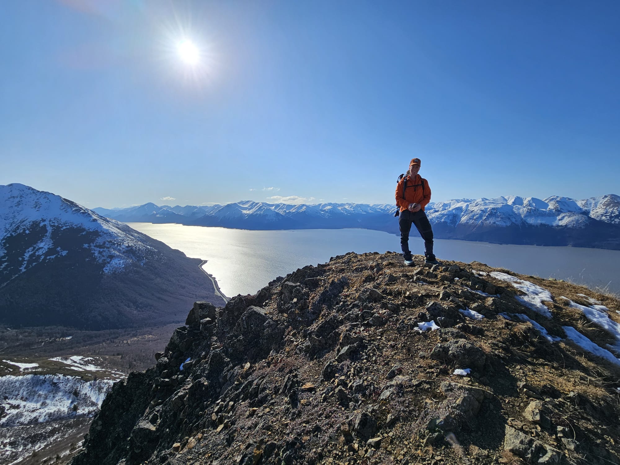 The author standing on a knob with the ocean and snowcapped mountains in the background